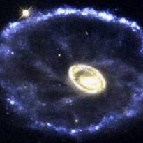 Галактика «Колесо Телеги». Редкое и красочное столкновение двух галактик можно увидеть на сделанном космическим телескопом Хаббла снимке галактики Колесо телеги, расположенной на расстоянии 500 миллионов световых лет от Земли в созвездии Скульптор. Ее удивительная особенность связана с расположением двух галактик, при котором меньшая – возможно, одна из небольших близлежащих галактик – с наклоном переместилась в центр основной. Подобно брошенному в озеро камню, столкновение вызвало волны энергии, на своем пути рассекающие газ и пыль. Распространяясь со скоростью 200 000 миль/ч, это космическое цунами оставляет за собой огненную бурю звездообразования.
